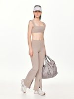 Full side-front view of the BEYOURA Giselle Broad Strap luxeFIT Sports Bra in taupe styled with hat and a gym bag
