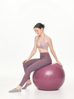Full side-front view of model in the BEYOURA Giselle Halter Strap luxeFIT Sports Bra in lilac sitting on fitness ball