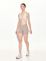 Full side-front view of the BEYOURA Giselle Halter Strap luxeFIT Sports Bra in off-white styled with water bottle