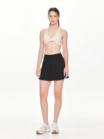 Full front view of the BEYOURA Giselle Twist luxeFIT Sports Bra in off-white styled with black skirt
